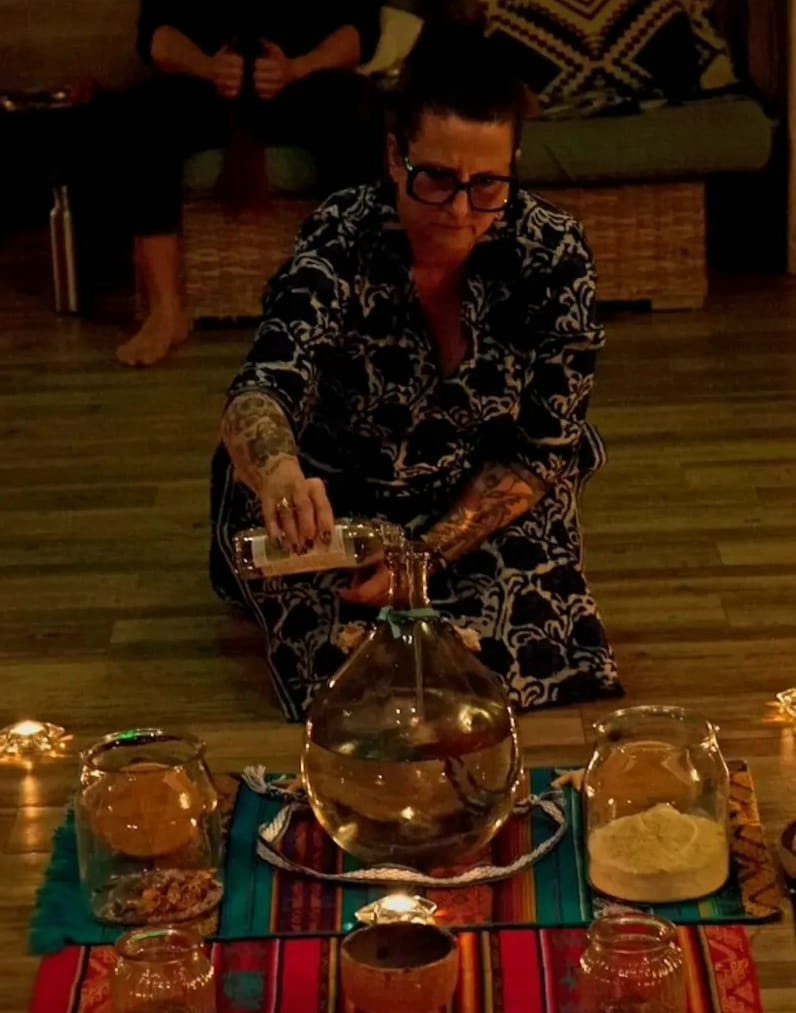Stéphanie verse de l'eau dans une grande carafe, entourée de bocaux et de bougies