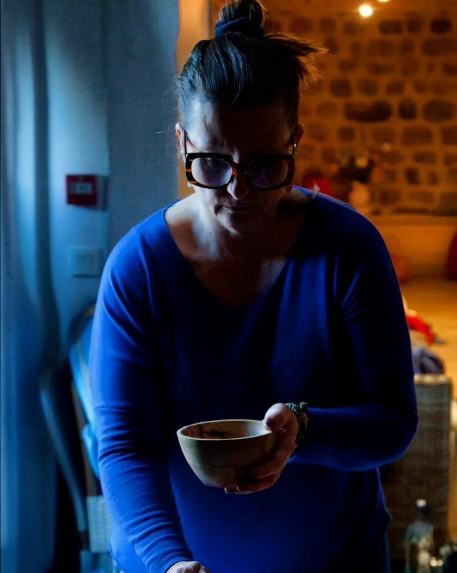 Stéphanie tient un bol de bois au-dessus d'une personne allongée